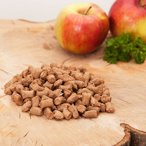 Pelletfutter auf Holzbrett mit Apfeldeko
